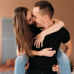 дівчина сидить на спині в хлопця і цілує його